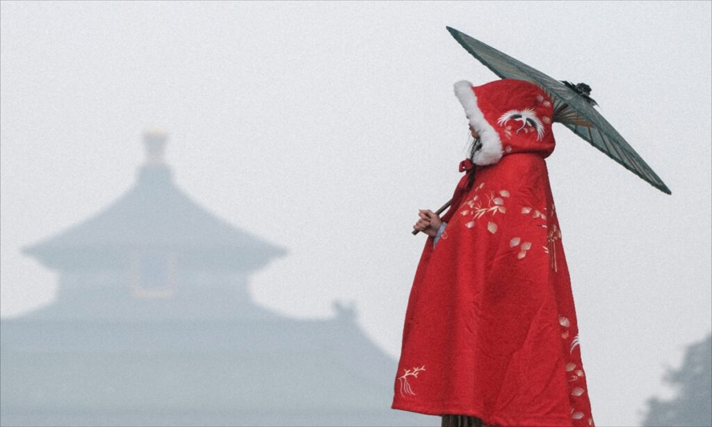 Woman with a retro red embroidered cloak holding an oil paper umbrella