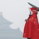 Woman with a retro red embroidered cloak holding an oil paper umbrella